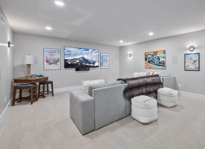 Expansive Theatre/Flex Room featuring light gray walls, recessed lighting, wall sconces, a flat-screen television, and light-colored carpeting