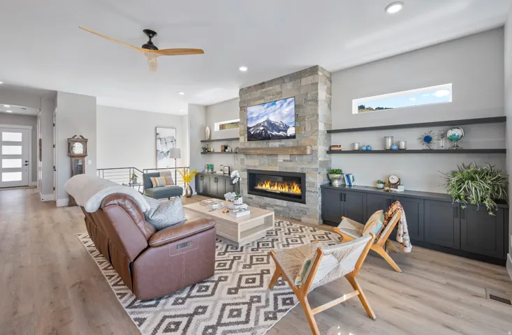 Open-concept living area featuring a stone-clad fireplace with an elongated linear insert, integrated wood mantle, and built-in shelving