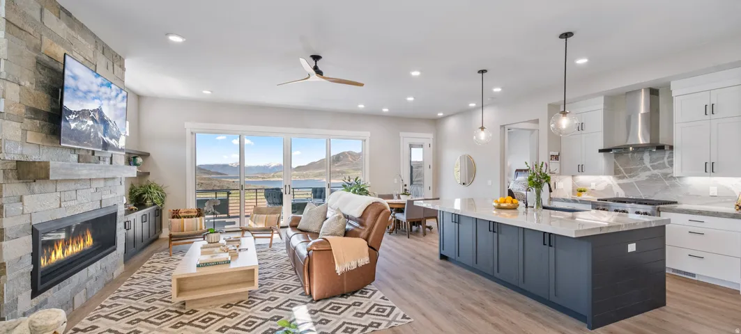 Open-concept living space featuring wood-finish flooring, a stone fireplace with a linear insert, and large sliding glass doors