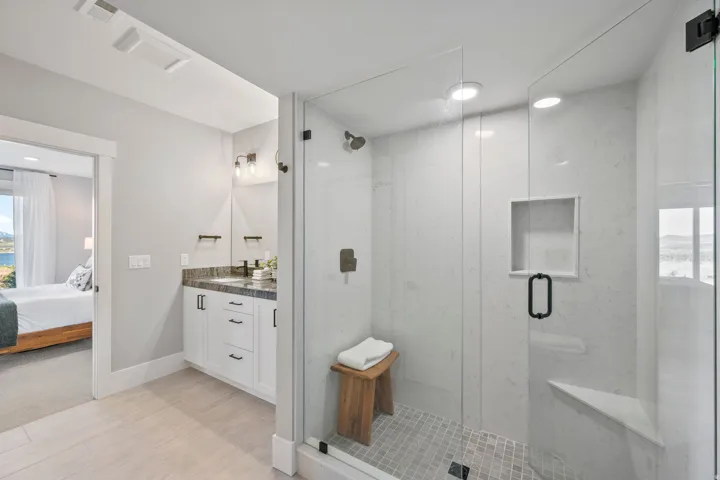 Glass-enclosed shower with a built-in bench, recessed niche, and stone tile floor