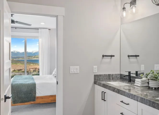 Ensuite Bathroom vanity featuring a single undermount sink, dark-toned countertop, and white cabinetry with matte black hardware