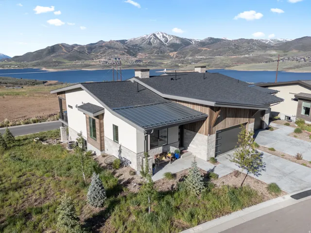 Contemporary residence featuring a dark asphalt shingle roof, wood siding accents, and light-toned stone veneer