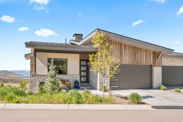Contemporary residence featuring a multi-textured facade with stucco, stacked stone, and vertical wood siding