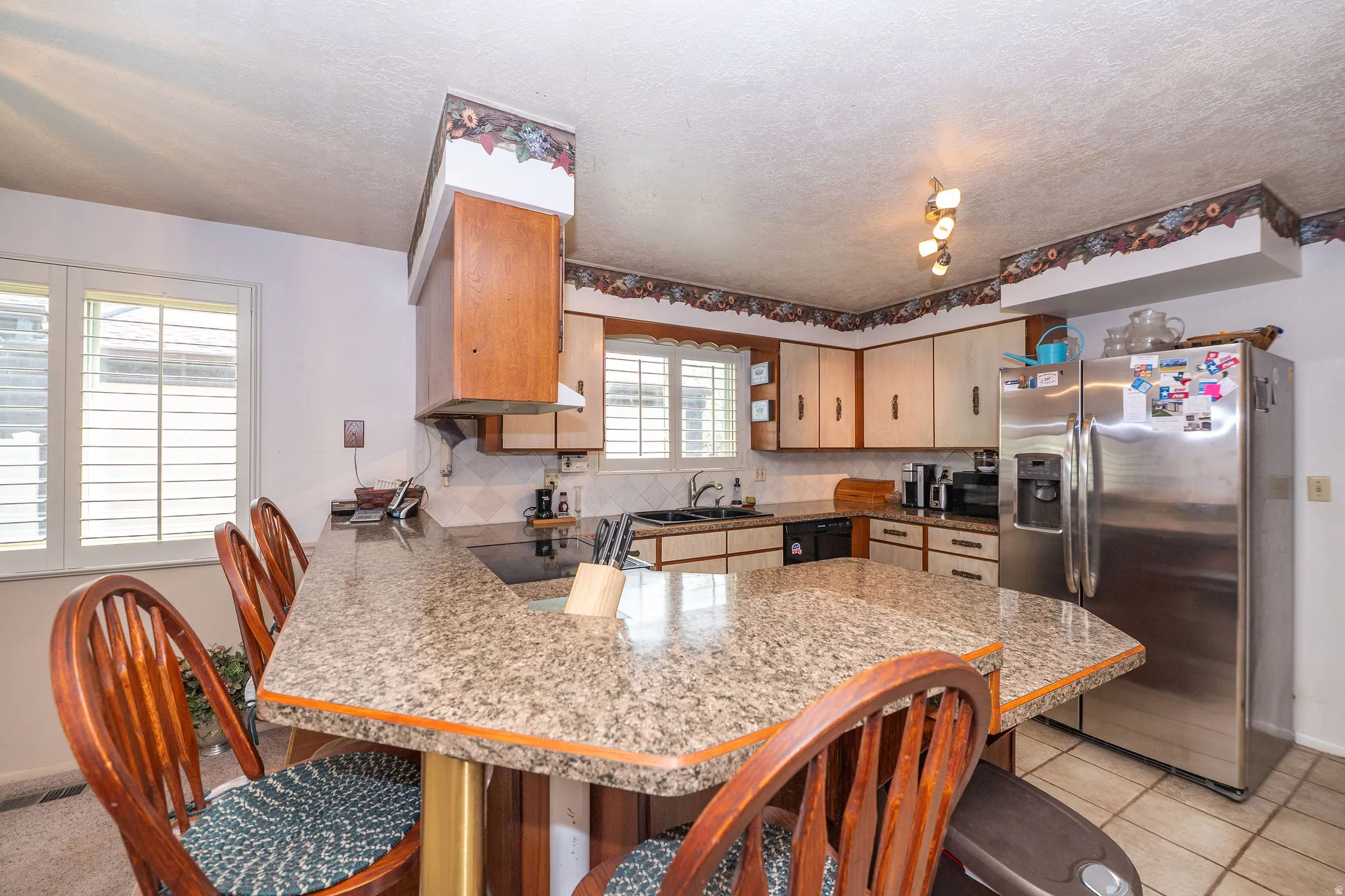 Kitchen featuring a peninsula breakfast bar with under-mounted suspended stools and tile floor.