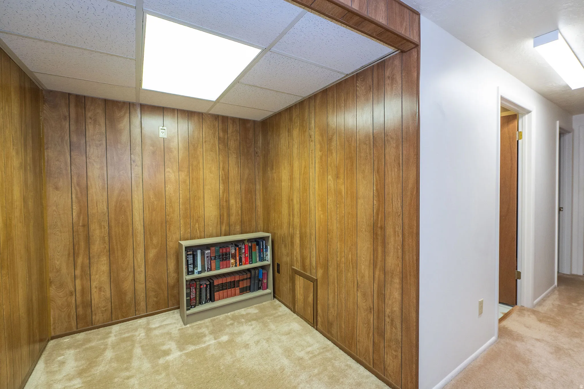 Room featuring wood-paneled walls, carpet flooring.