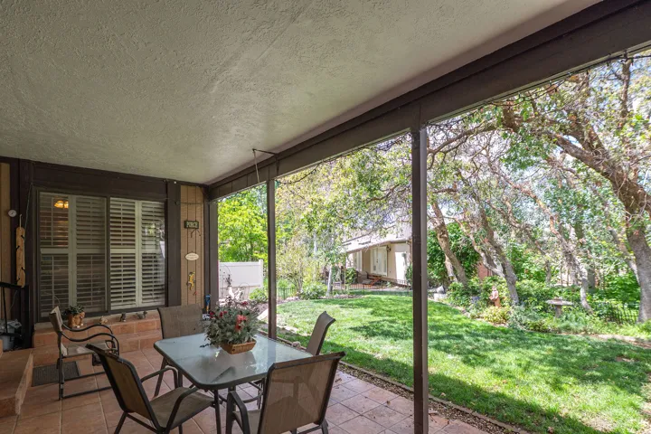 Covered patio featuring a terra cotta tile floor and dark wood-tone support beams