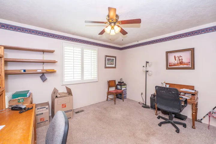 Interior room featuring light-toned carpet flooring, and a ceiling fan with integrated lighting