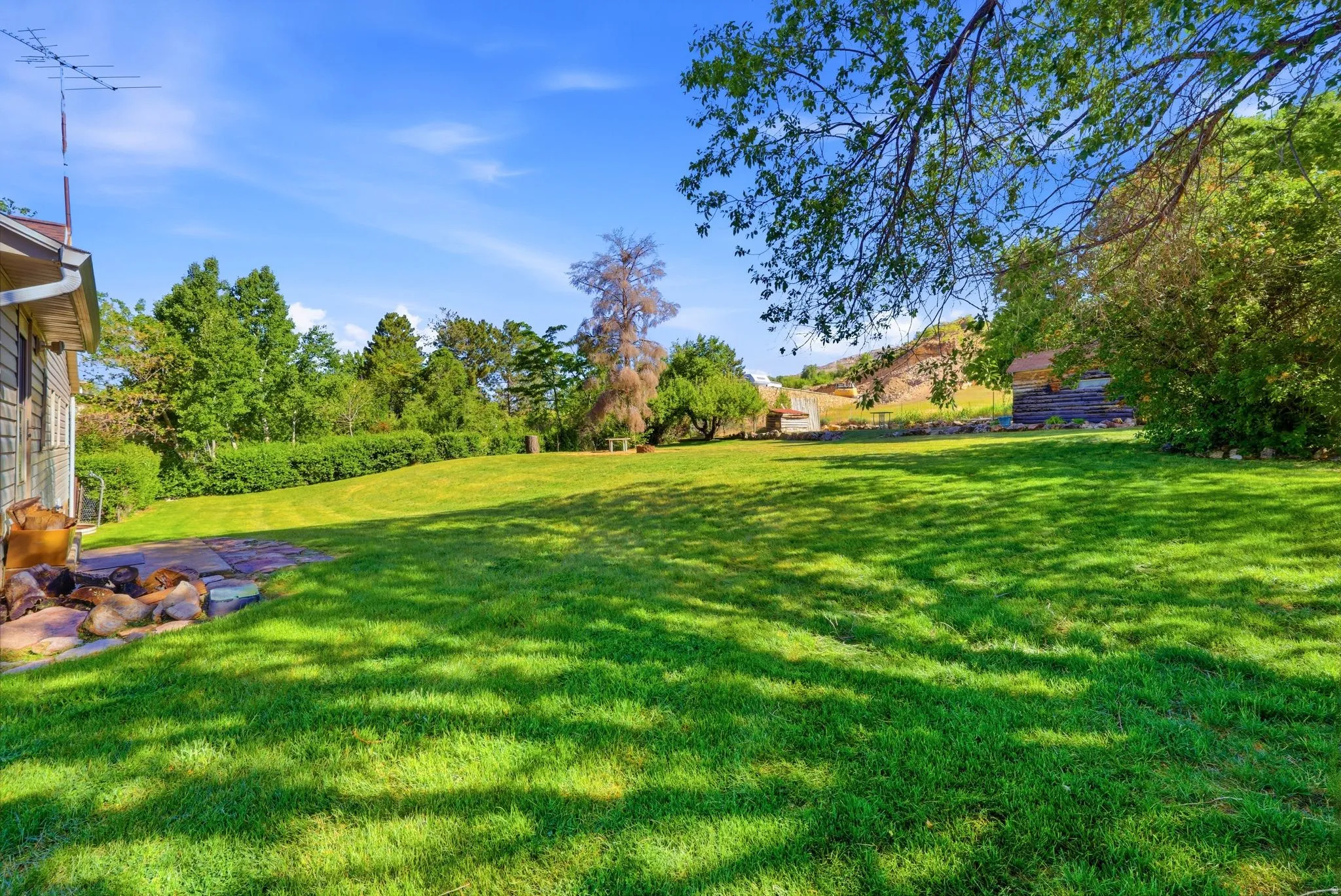 Expansive green lawn with mature trees and a clear blue sky