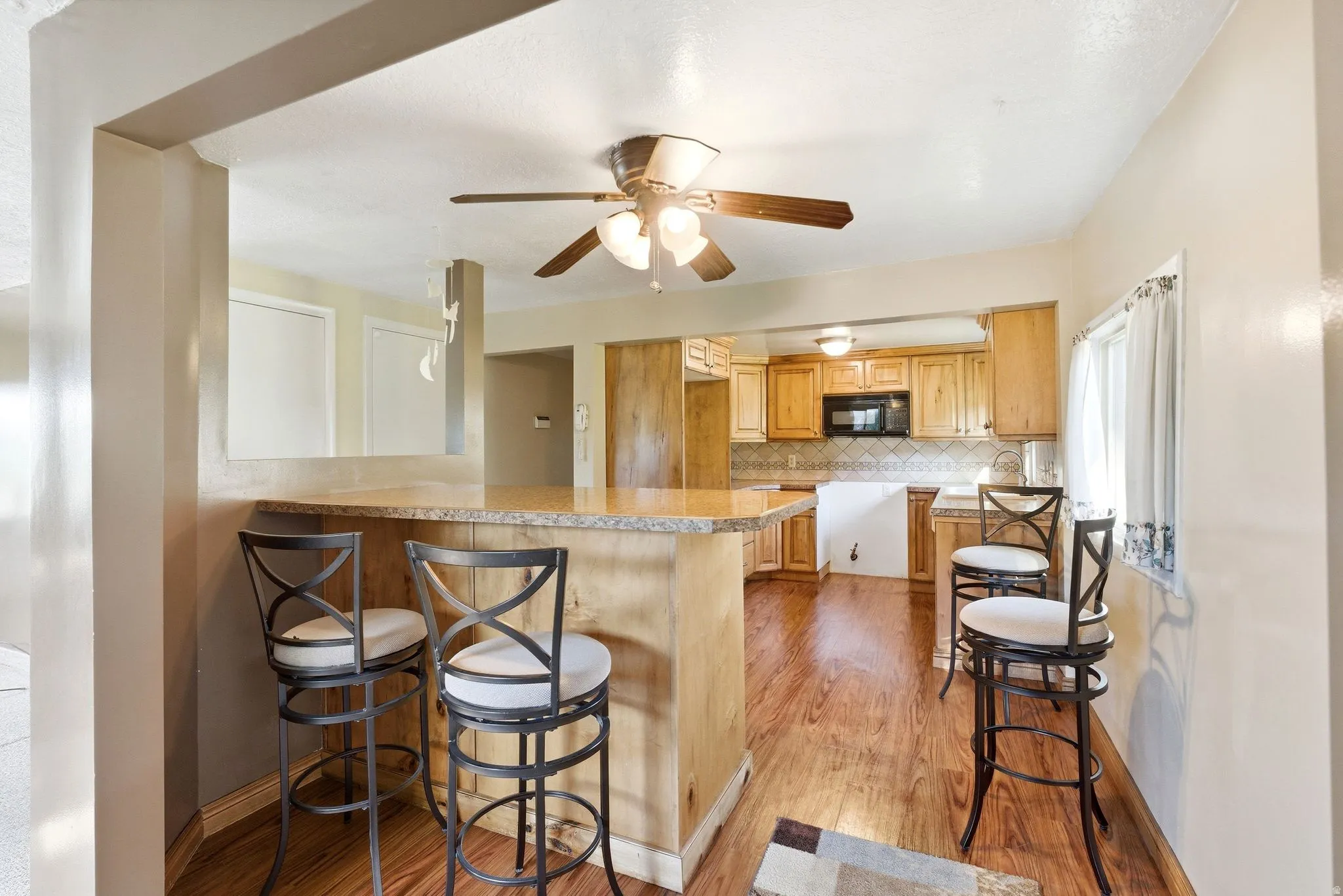 Kitchen featuring wood-finish flooring, natural wood cabinetry, and a built-in microwave