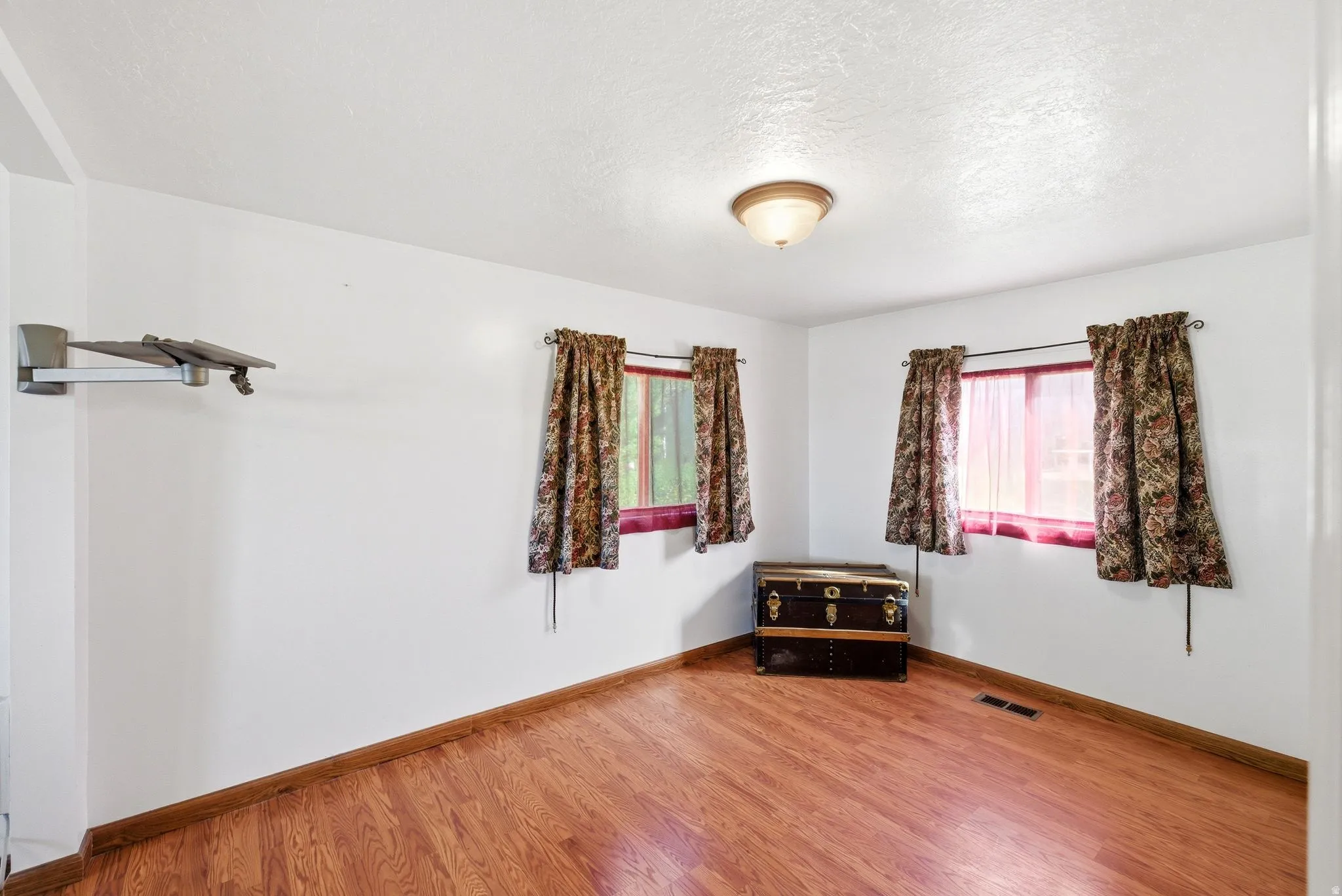 Bright interior space with wood-finish flooring, white walls, and a ceiling-mounted light fixture