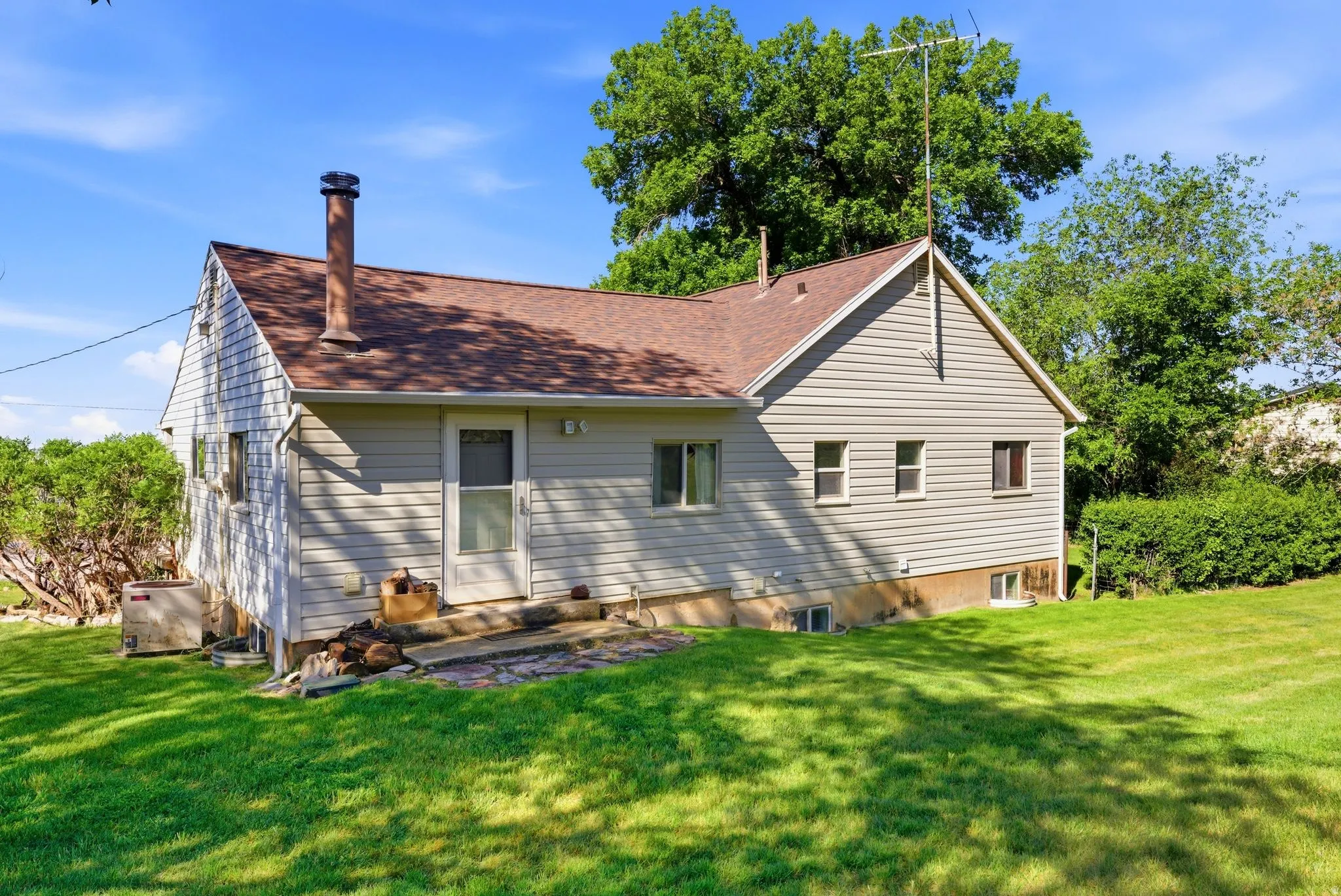 Exterior featuring light-toned siding and a brown shingle roof
