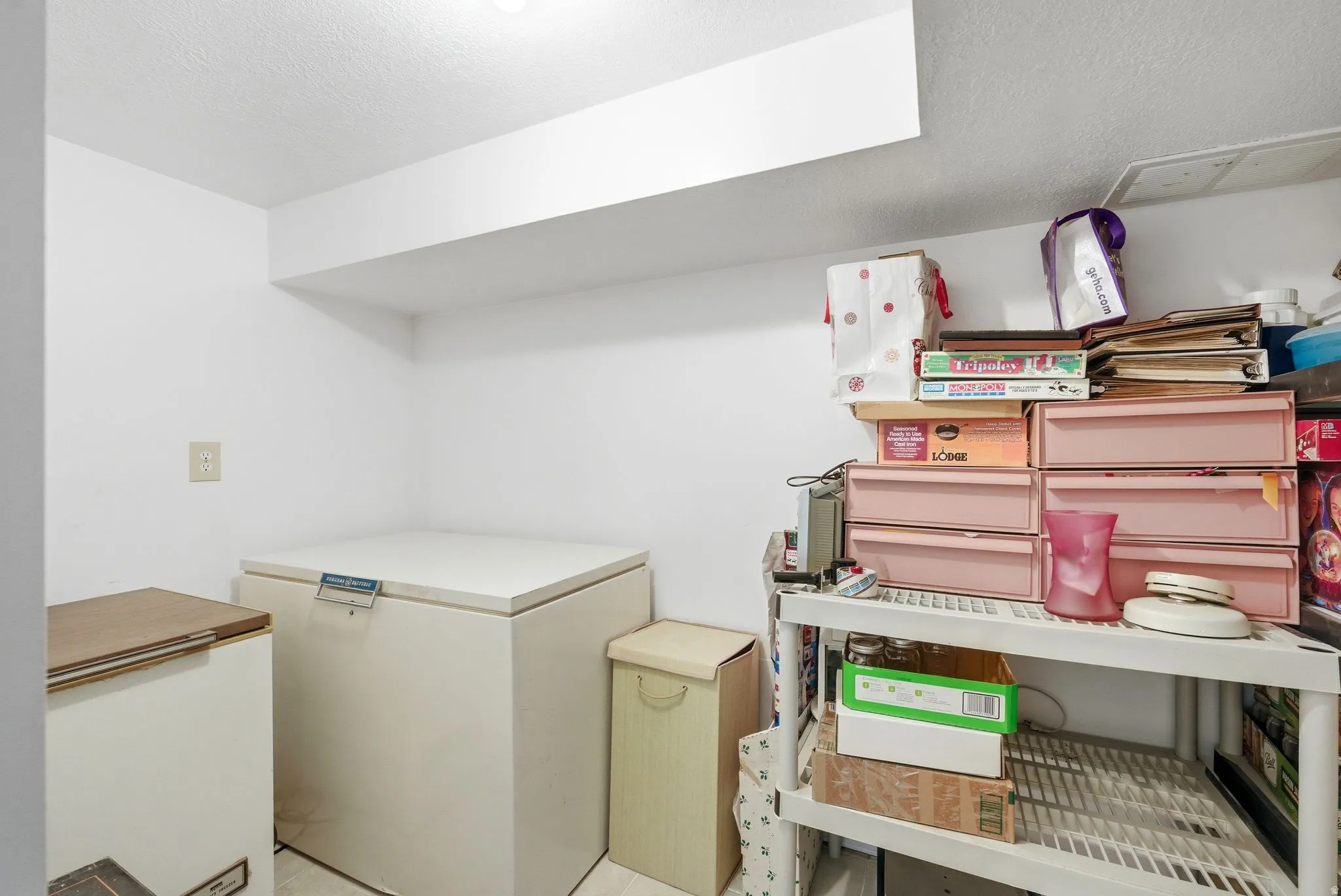 White painted walls with a recessed light fixture, exposed ceiling joist, and electrical outlet