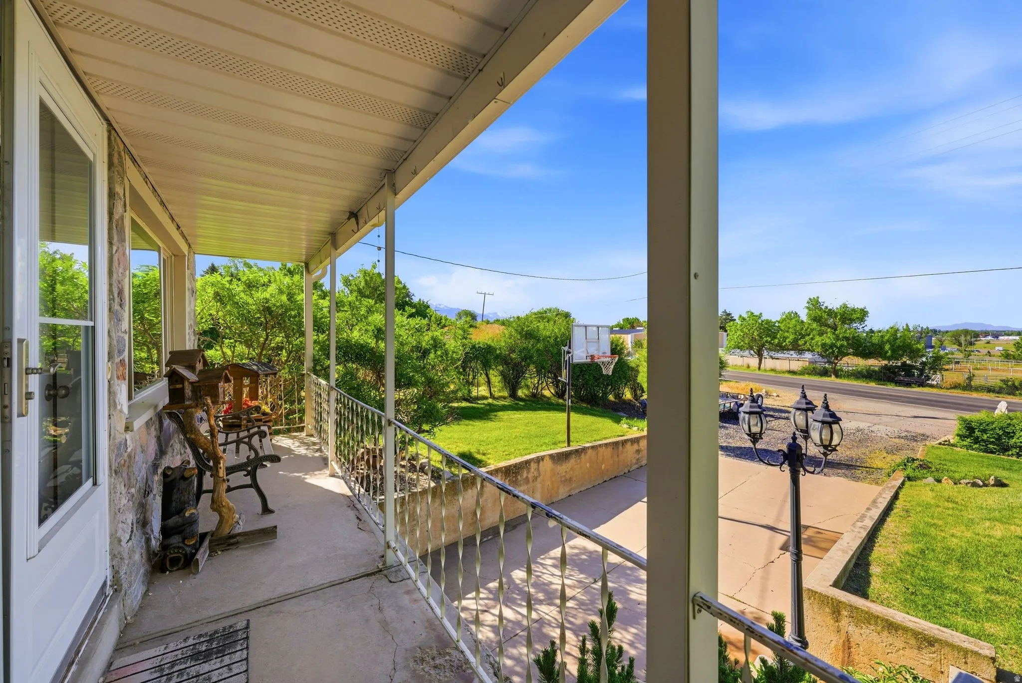 Covered front porch featuring a stone-clad exterior, white framed windows, and a metal railing