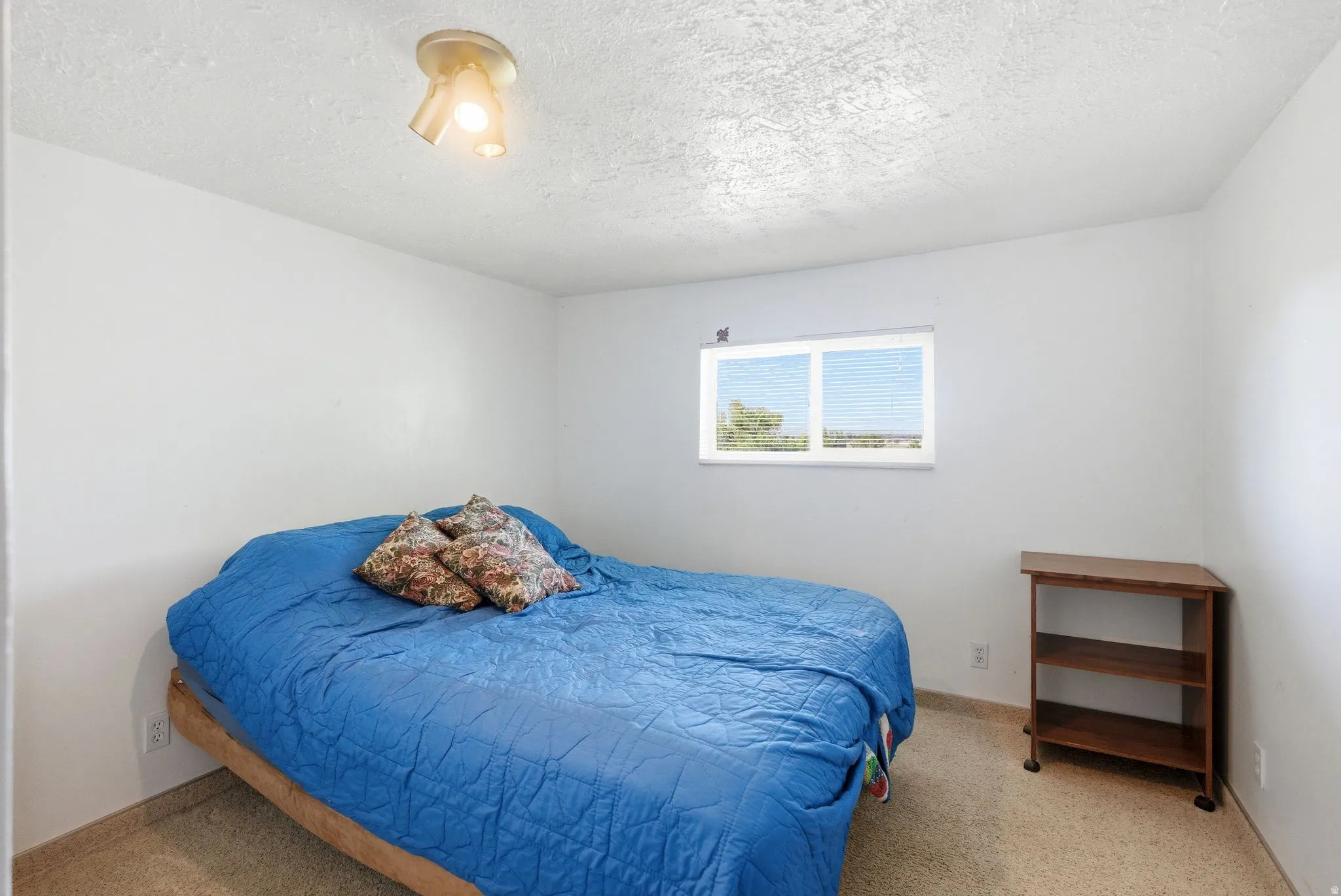 Bright room with neutral wall paint, textured ceiling, and a double-paned window