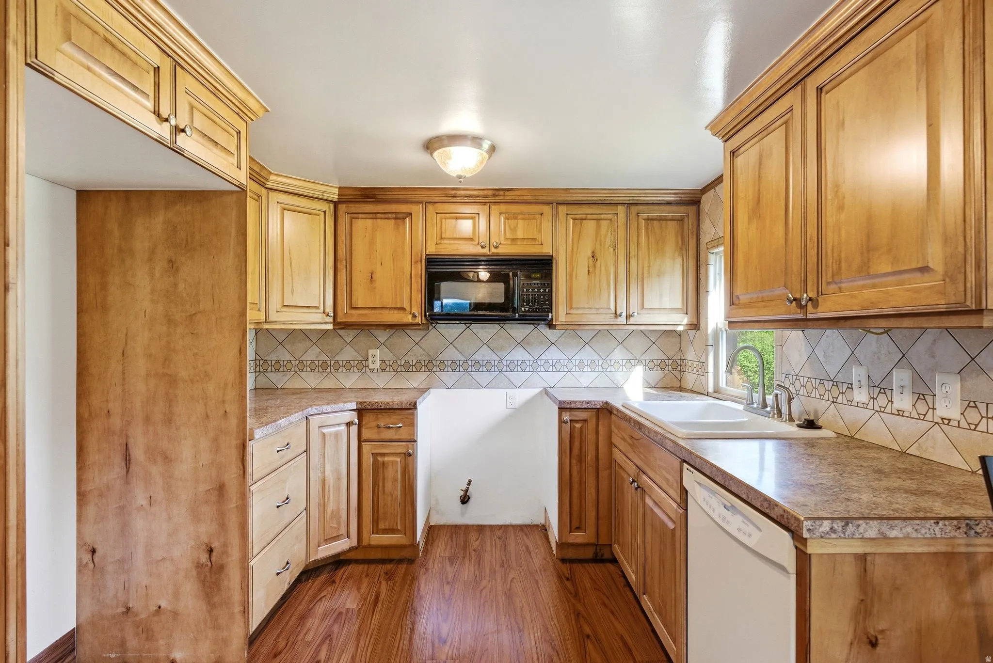 Kitchen featuring wood-finish cabinetry, solid surface countertops, and a tile backsplash