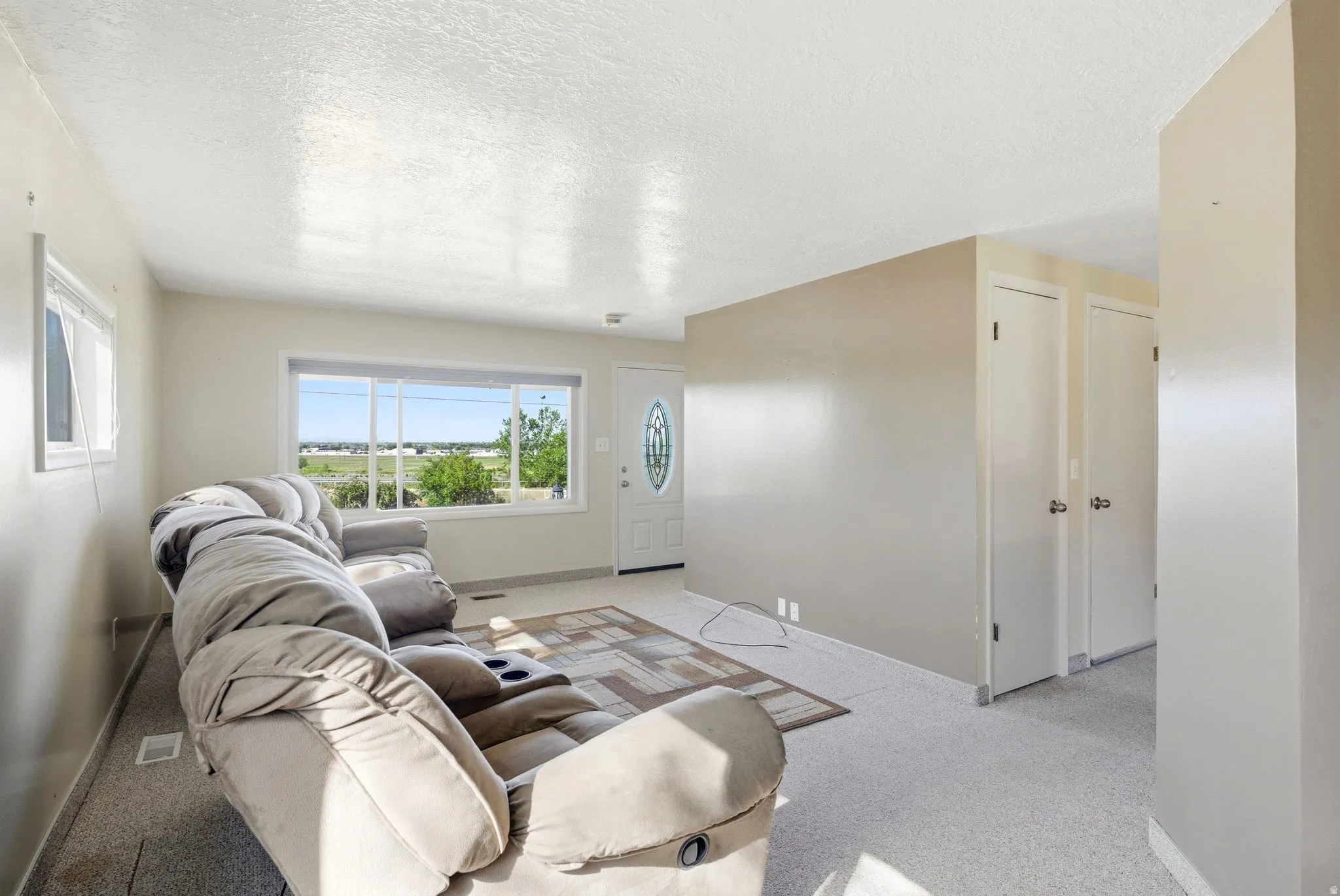 Living area featuring light-colored walls and carpet flooring