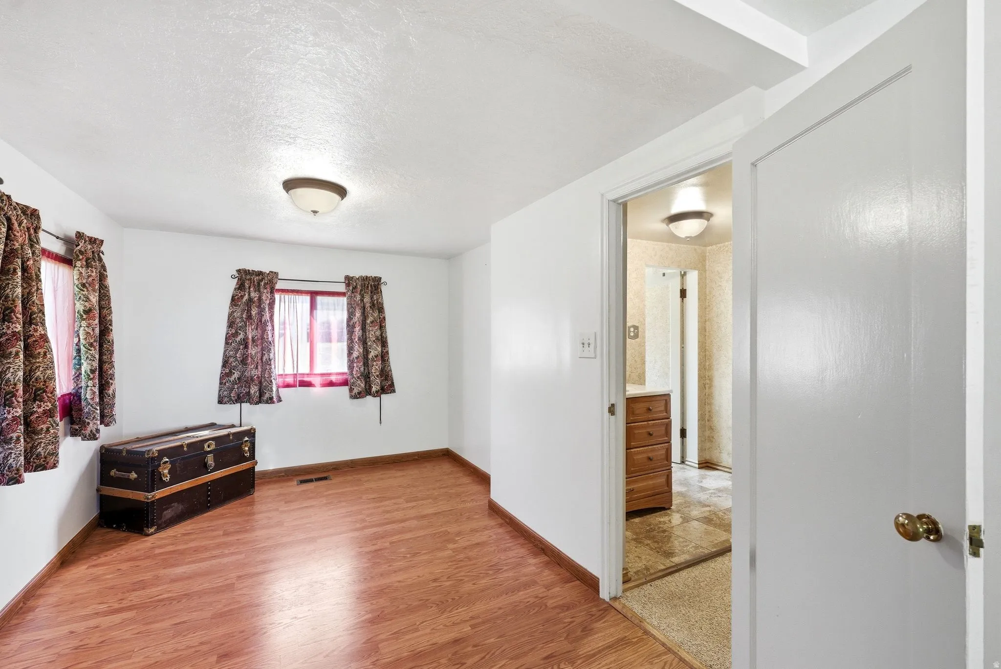 Interior room featuring wood-finish flooring and two windows with valances and curtains