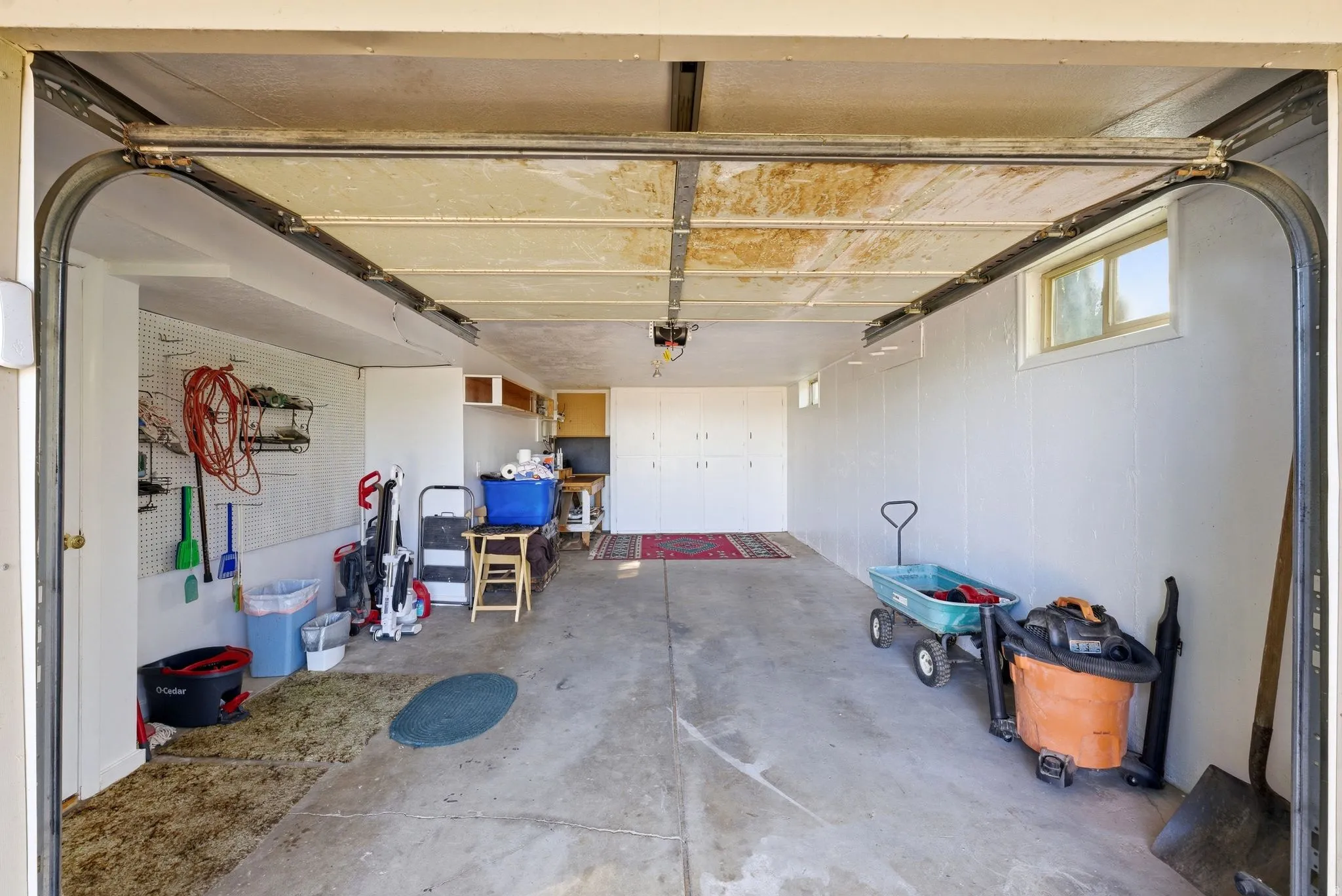 Spacious garage featuring a concrete floor, built-in cabinetry, and multiple windows providing natural light