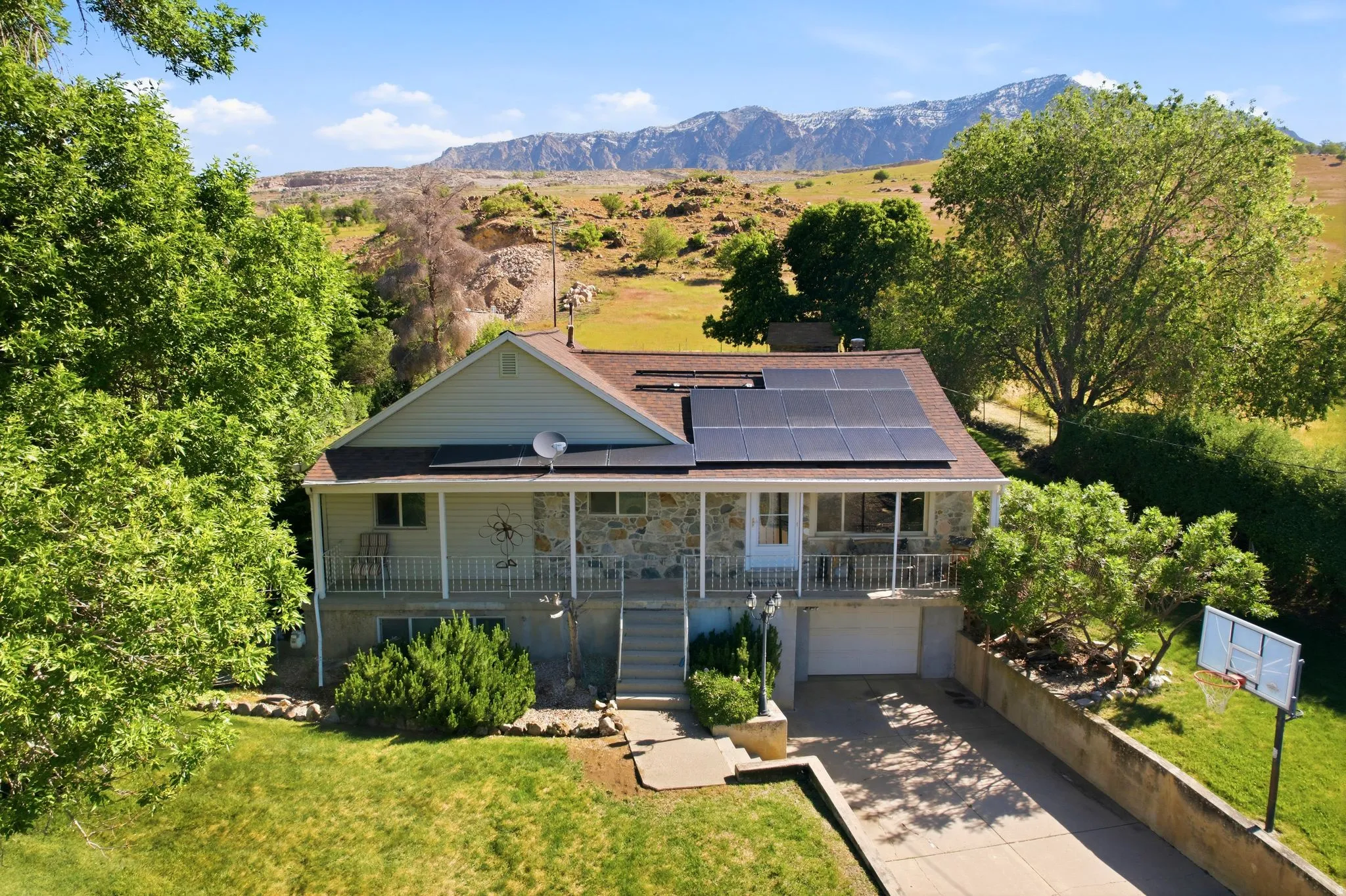 Split-level residence featuring a stone and siding exterior, expansive solar panel array, and a covered upper-level balcony