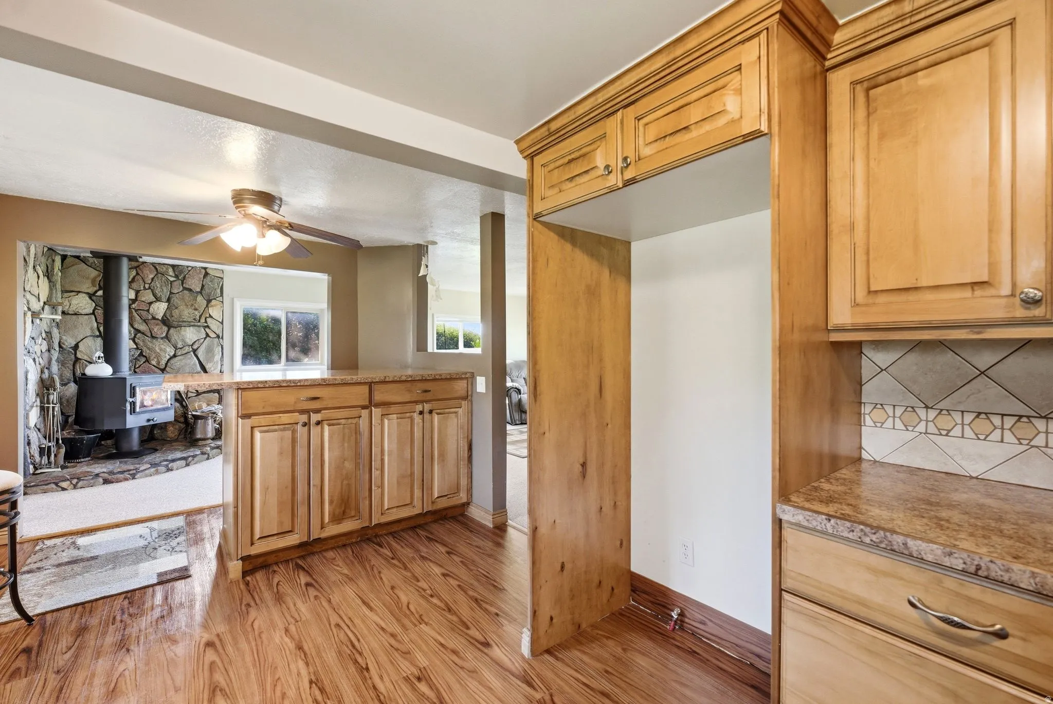 Kitchen area featuring wood-finish flooring, light wood cabinetry, and a patterned tile backsplash