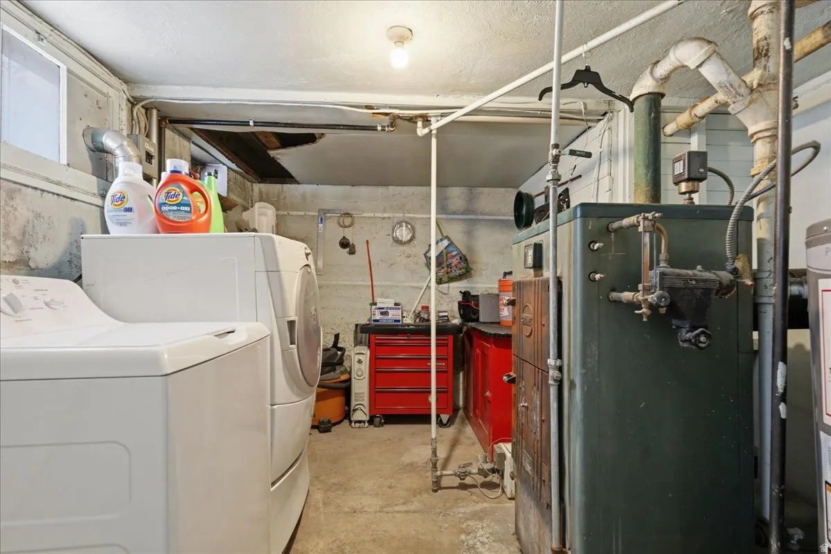 Utility space featuring a washer and dryer, concrete flooring, and exposed mechanical systems