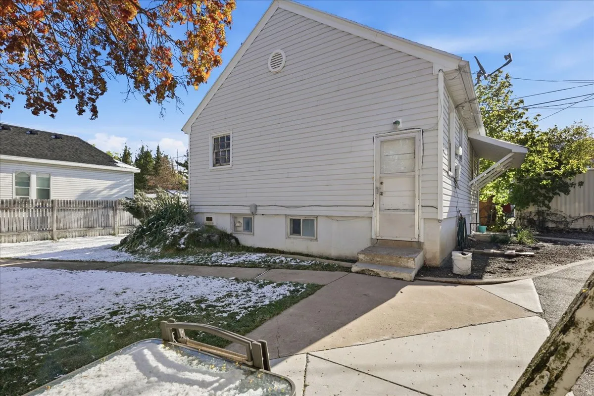Rear exterior featuring light-colored siding, a concrete patio, a private entry, and a side yard with a partial fence