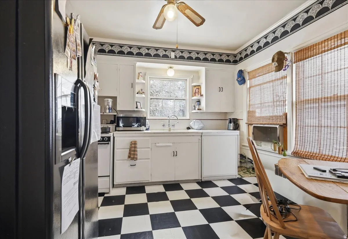 Kitchen featuring checkerboard flooring, white cabinetry, and a double-basin sink below a window