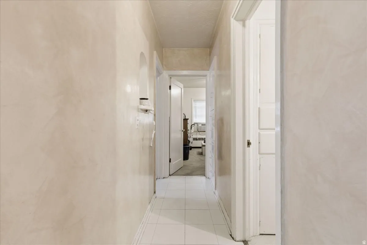 Hallway featuring light-toned walls, white tile flooring, and white trim