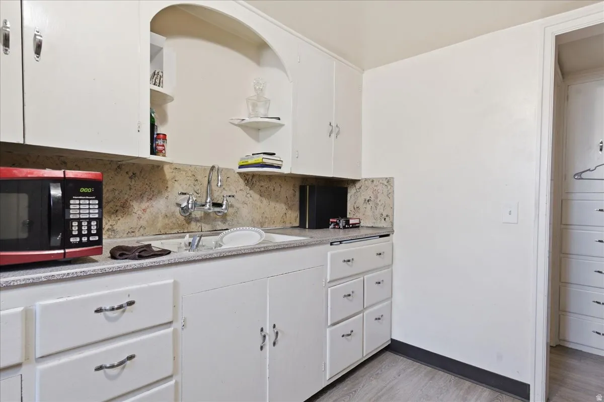 Kitchenette featuring white cabinetry, a single basin sink, a speckled countertop, and a matching backsplash