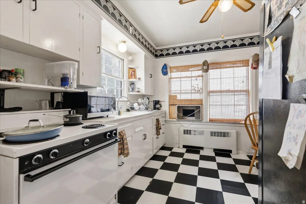 Kitchen featuring checkerboard flooring, white cabinetry, a built-in sink, and double windows with bamboo blinds