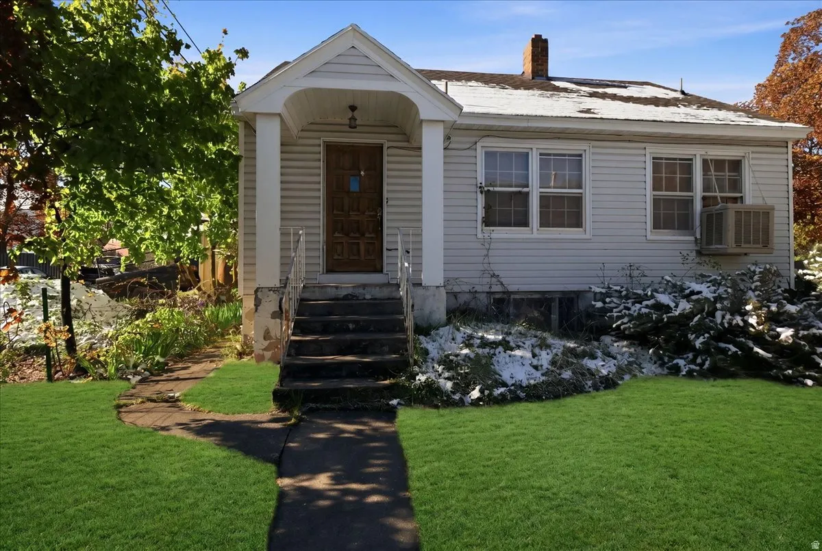 Front exterior featuring white siding, a covered porch with white columns, and a dark brown entry door