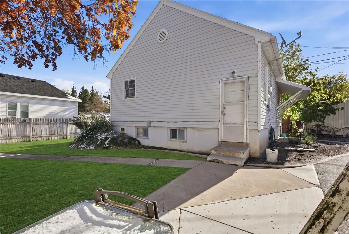 White siding exterior with a side entrance featuring a small awning and concrete steps