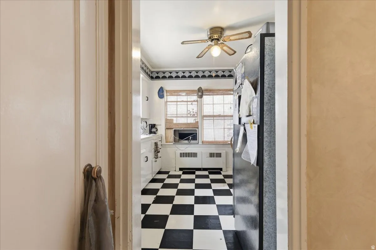 Kitchen featuring black and white checkerboard flooring, white cabinetry, a double window, and a ceiling fan with light fixture