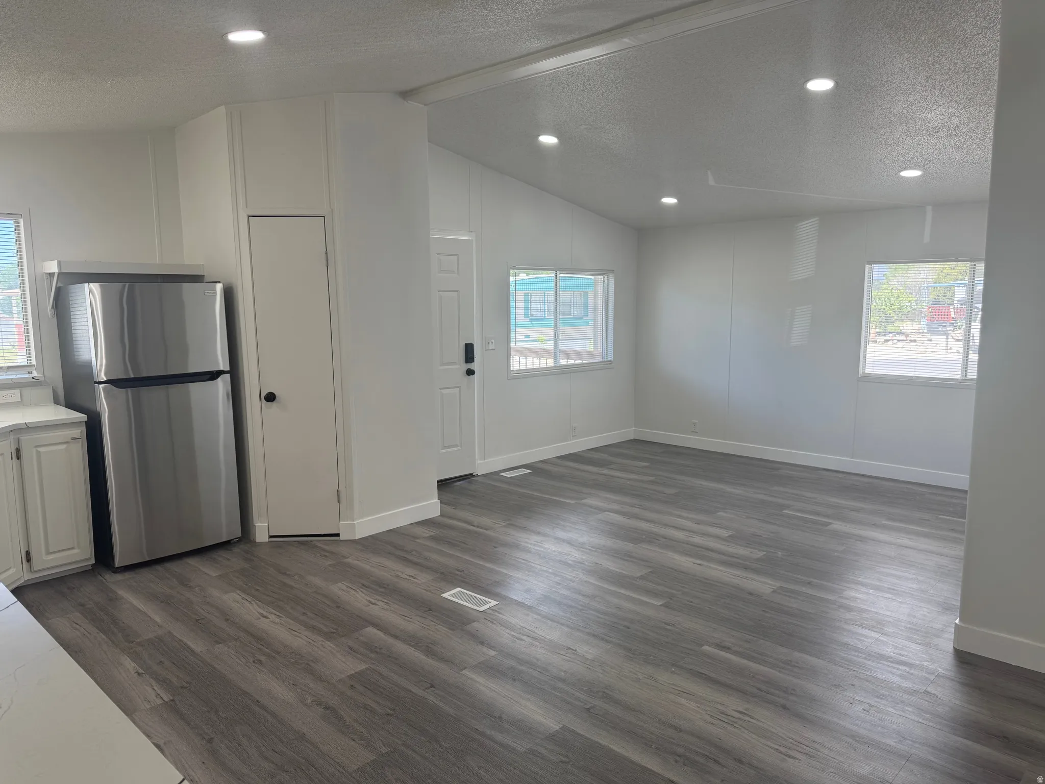 Open-concept living area featuring wood-finish flooring, recessed lighting, and multiple windows
