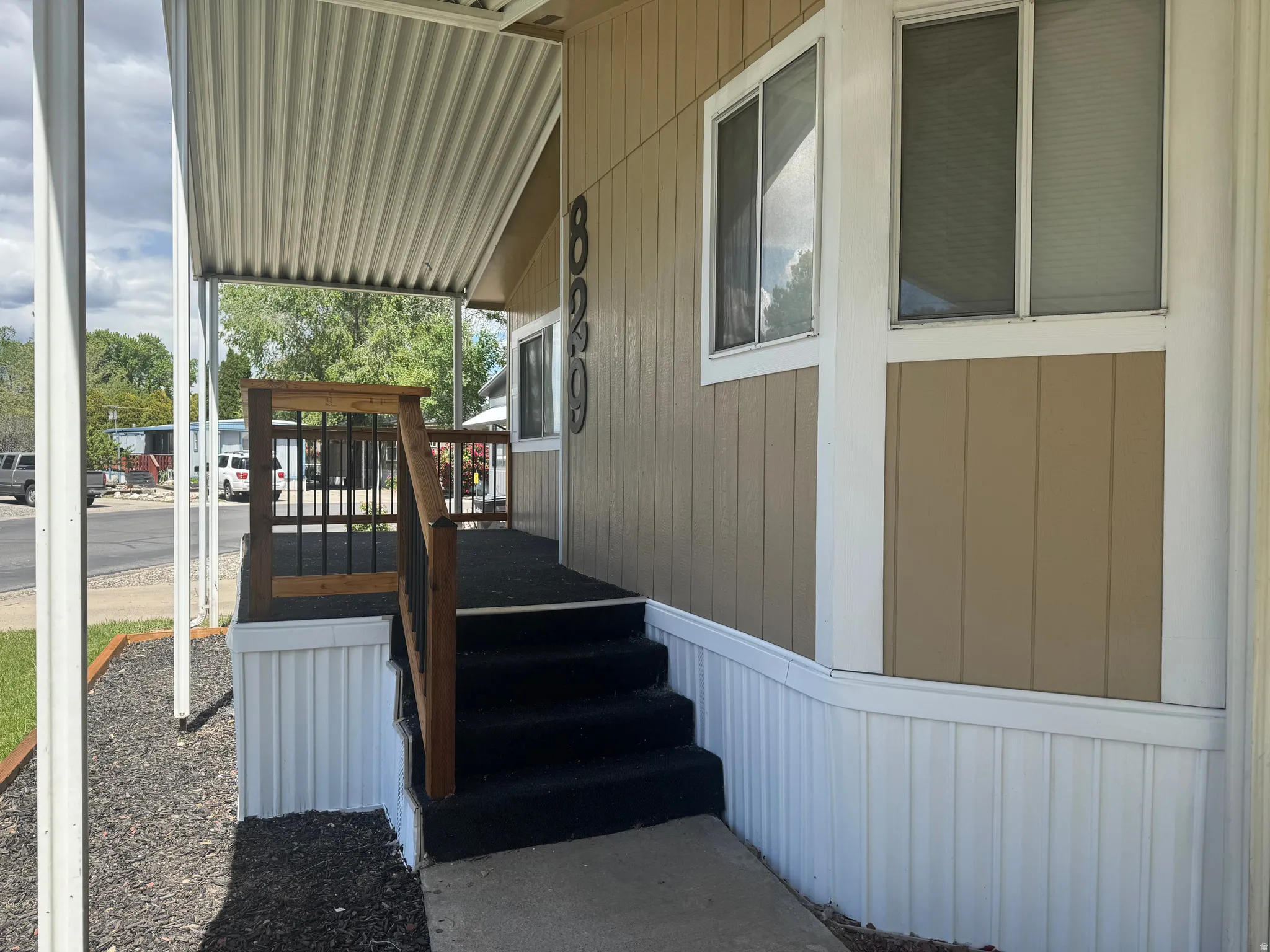 Covered porch entry featuring a wood railing with black metal balusters