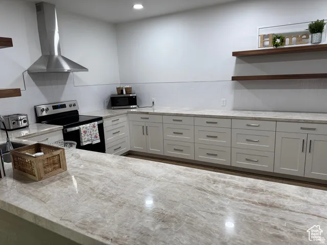 Kitchen featuring extensive stone countertops, light cabinetry, and wood-finish open shelving