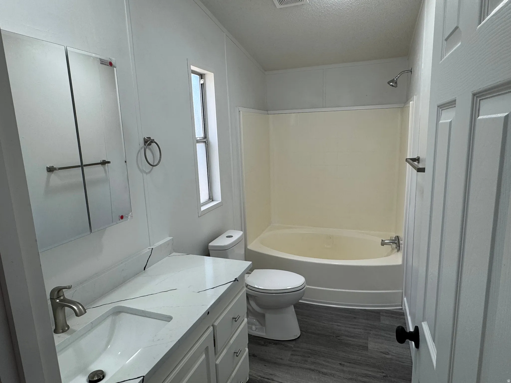 Bathroom featuring a white vanity with an integrated sink, brushed nickel faucet, and a wall-mounted mirrored medicine cabinet