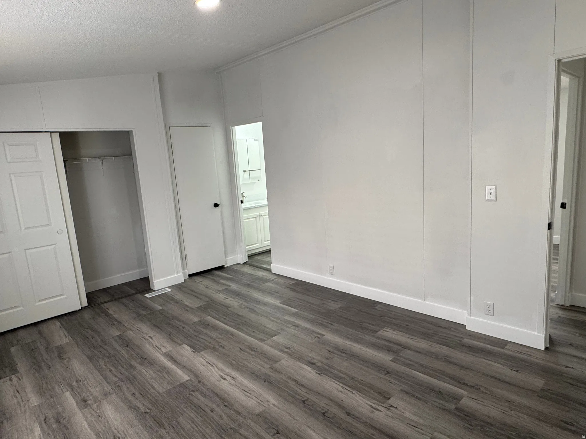 Spacious room featuring wood-finish flooring, white paneling, and baseboards