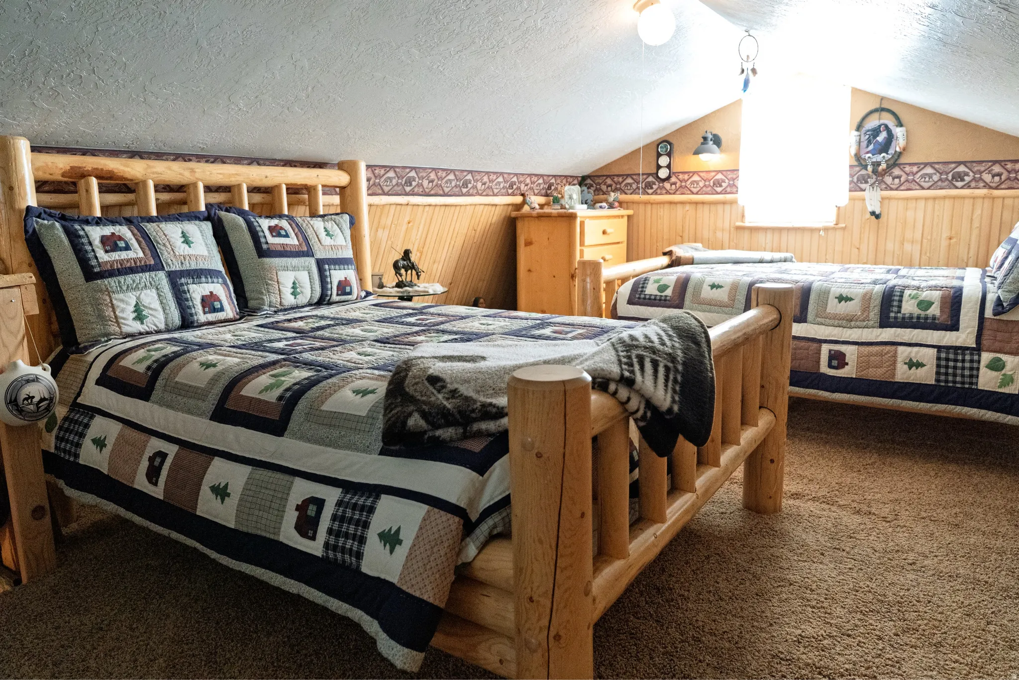 Sloped ceiling room featuring light-toned wood paneling and natural wood bed frames
