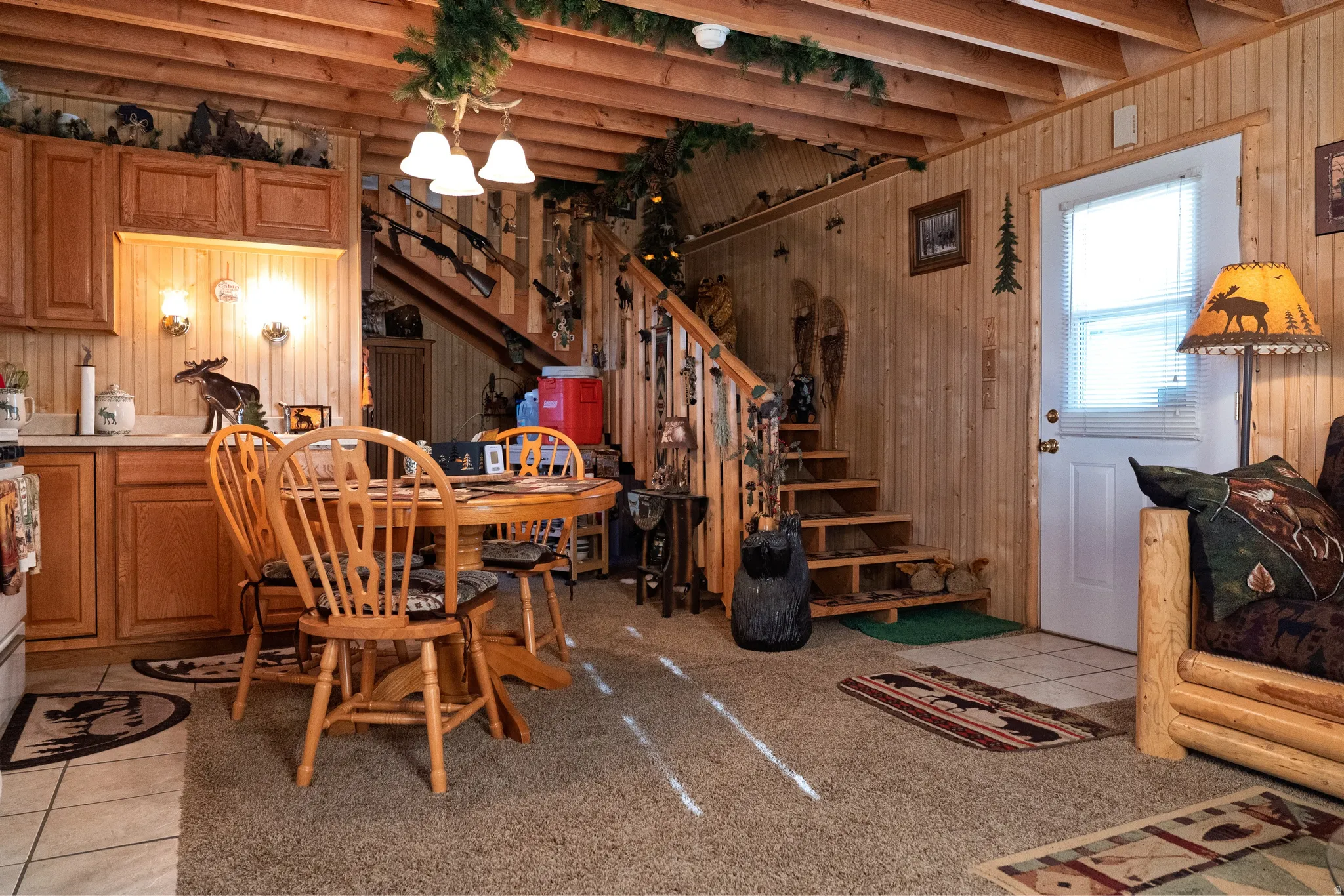 Open-concept interior featuring wood paneling, exposed wood beam ceiling, and a staircase with a wood railing