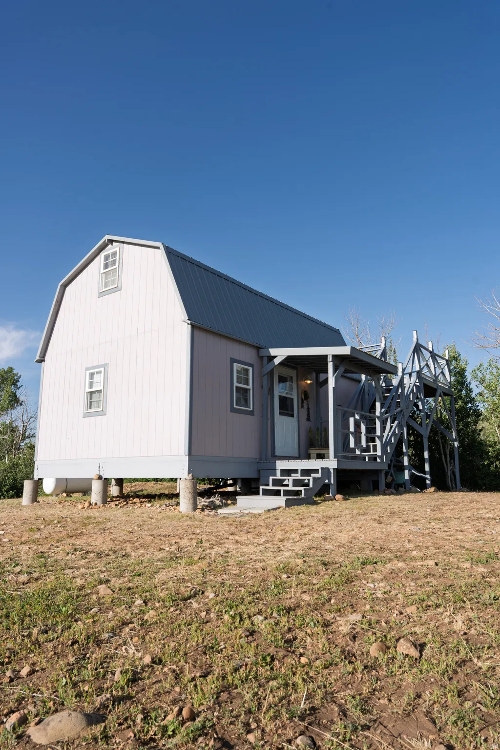Gambrel-style structure featuring a metal roof, exterior siding, and an elevated foundation