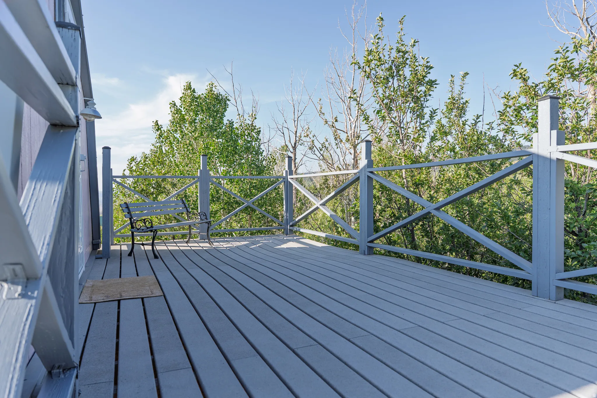 Spacious outdoor deck with light gray wood-finish decking and matching cross-pattern railings