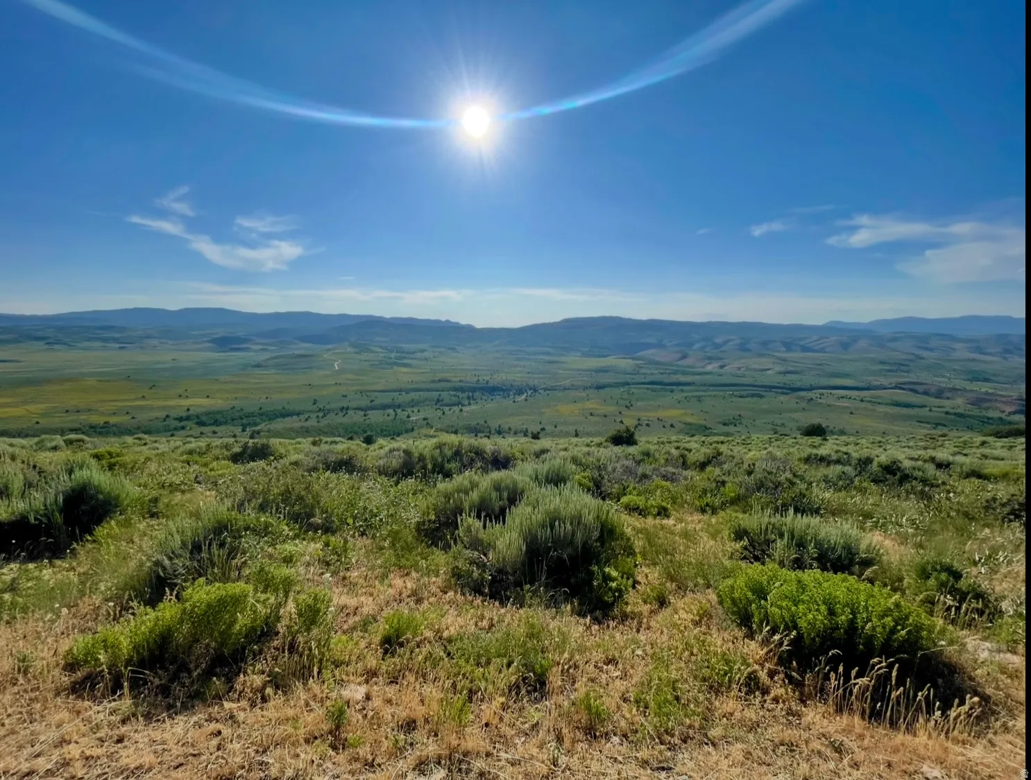 Expansive landscape featuring rolling hills and distant mountains under a clear sky