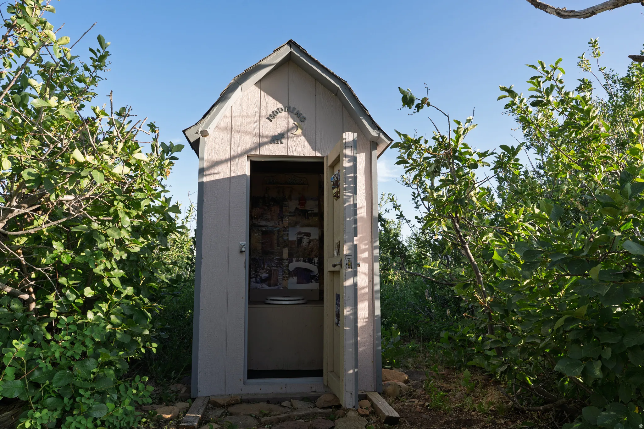 Compact outdoor structure with light-toned vertical siding and a dark-shingled gable roof