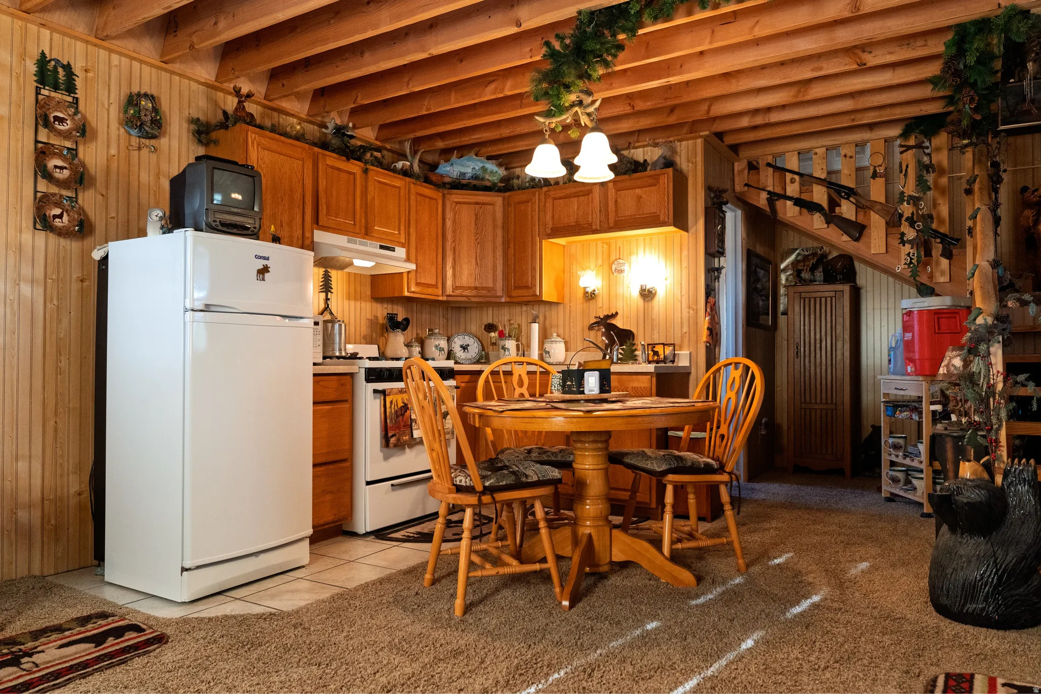 Kitchen and dining area featuring wood cabinetry, white appliances, and a round wooden dining table with four chairs