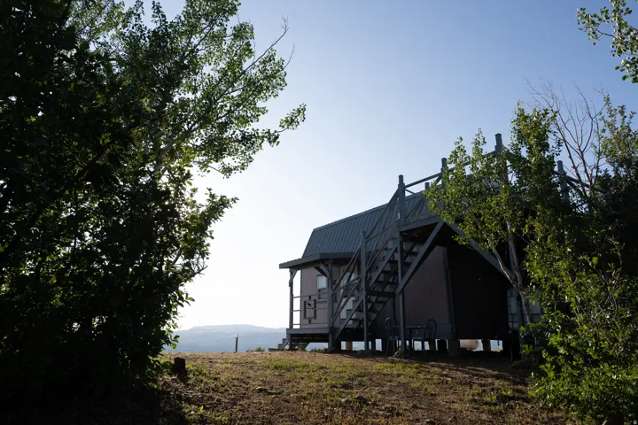 Elevated property featuring a light-colored exterior with dark trim and a dark metal roof