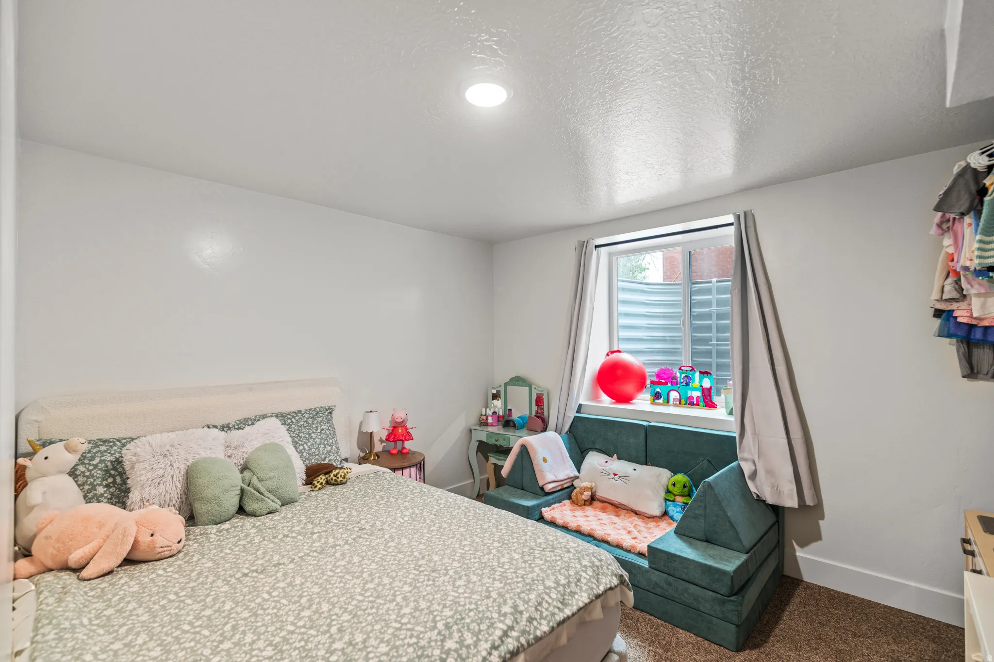 Bedroom featuring a carpeted floor, white walls, and a window with a window well