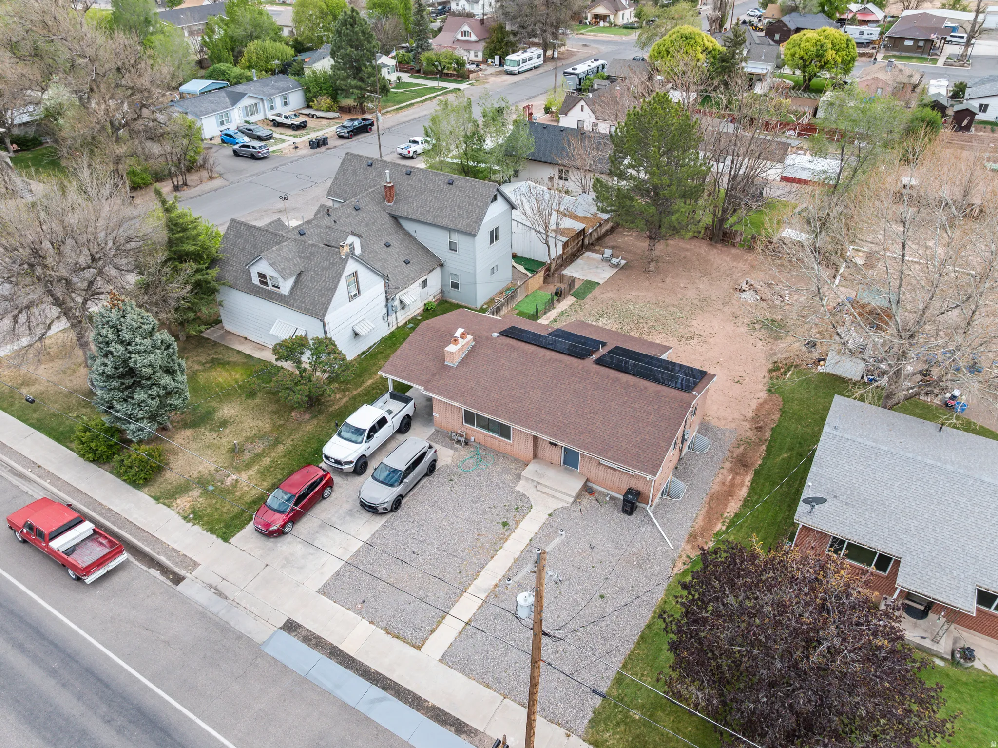 Brick exterior residence featuring a brown shingle roof with visible solar panels