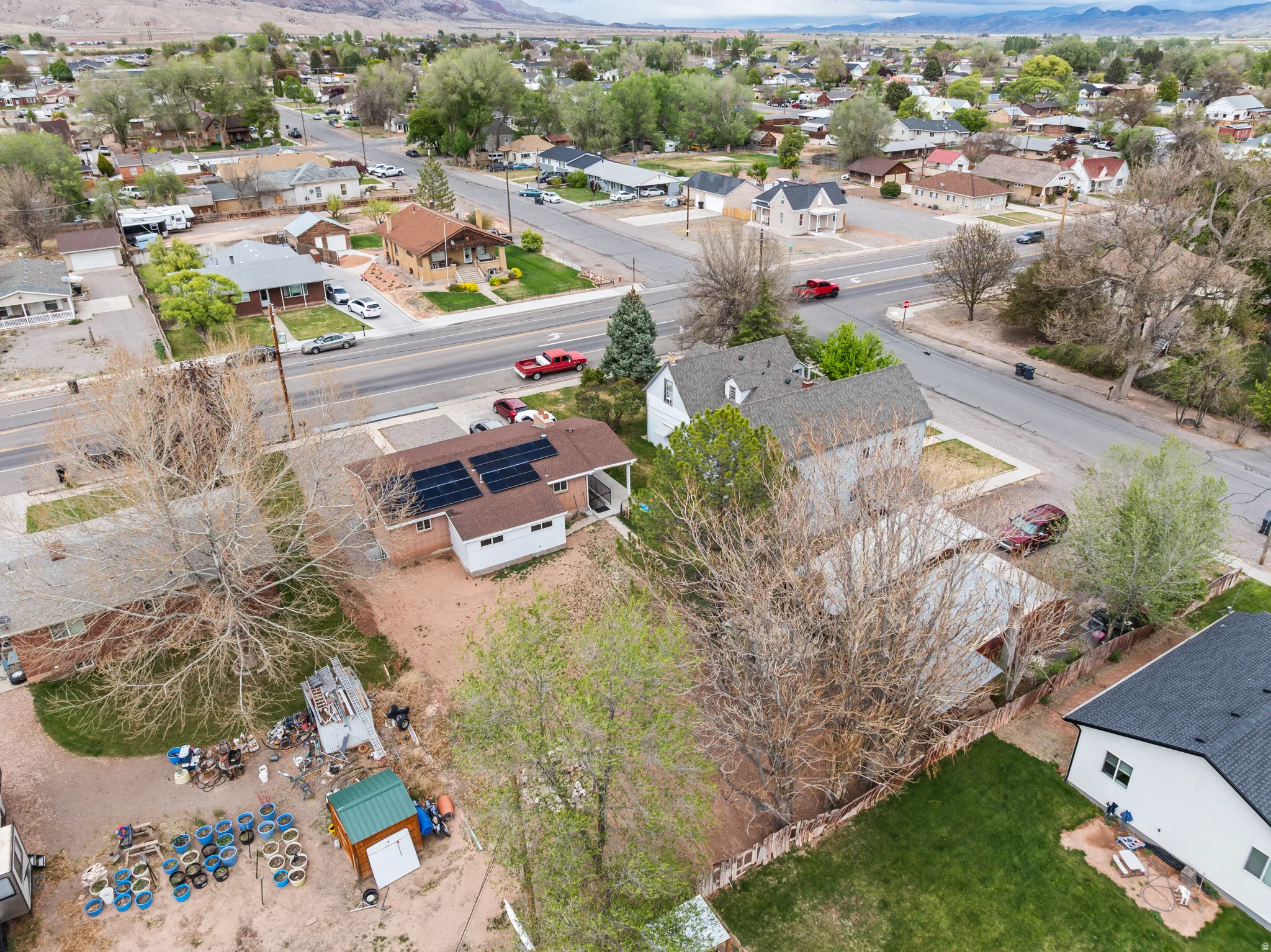 Aerial perspective showcasing a residential property with solar panels, a brown shingle roof, and light-colored siding