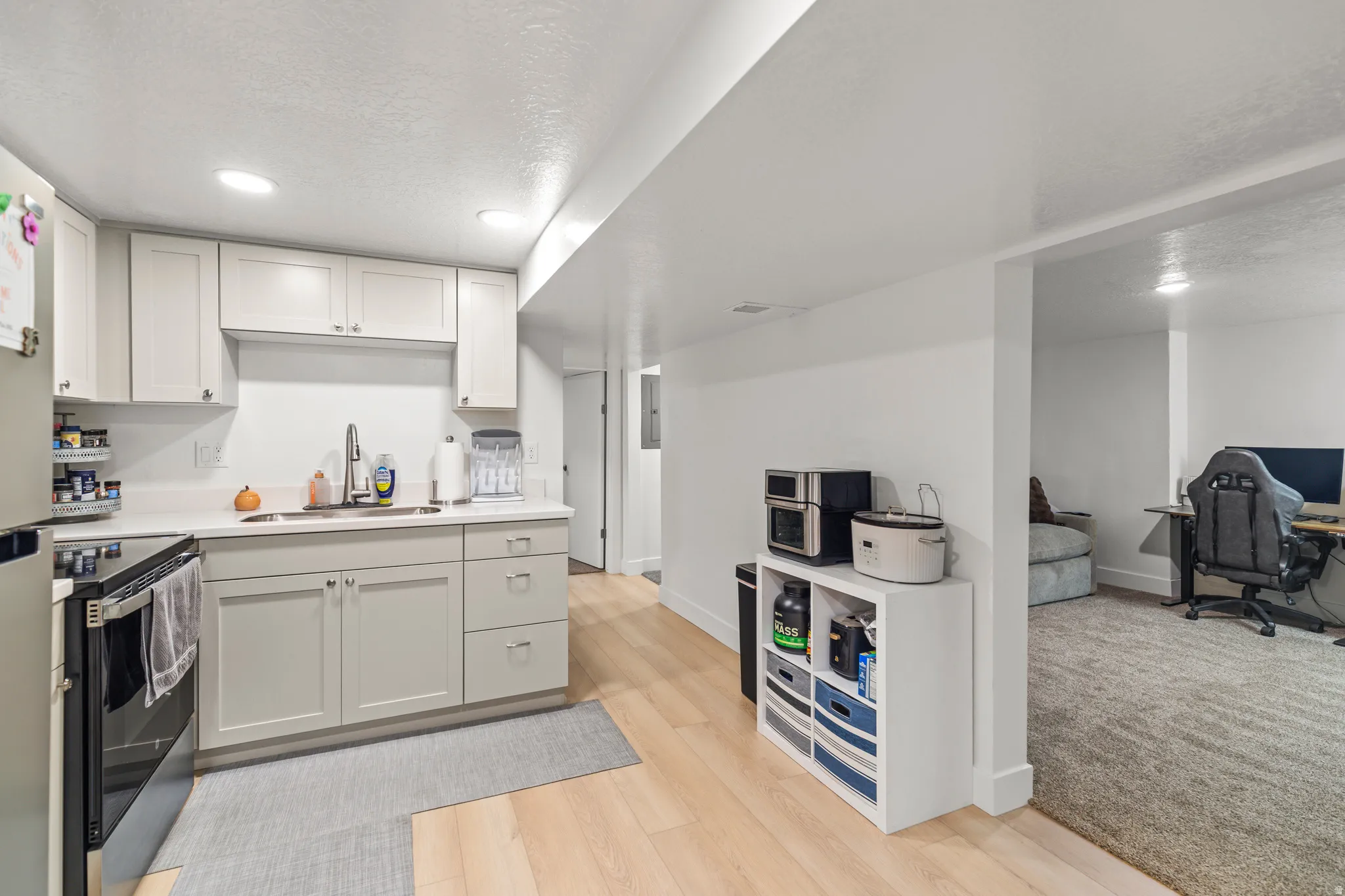 Modern kitchen featuring light cabinetry, white countertops, a stainless steel sink with a gooseneck faucet, and recessed lighting